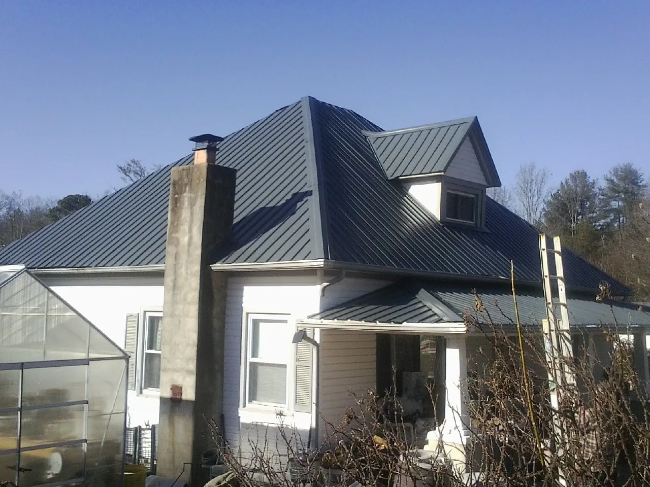 Dark blue standing seam metal roof on a white farmhouse with dormer — Slate & Tile Roof Repair by Roofing Brothers in Bandera
