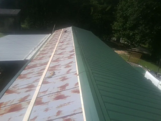 Old rusted panels beside newly installed green metal roofing — Wind Damage Roof Repair by Roofing Brothers in Bandera