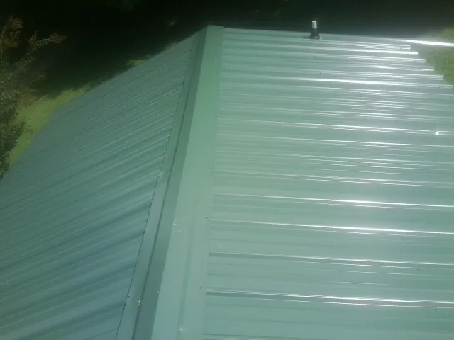 New green metal panels meeting at the ridge of a roof — Flat Roof Repair work by our crew in Bandera