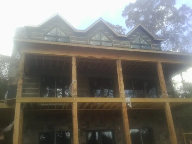 Dormers and porch framing on a large log home under construction — Roof Coating work by our crew in Bandera