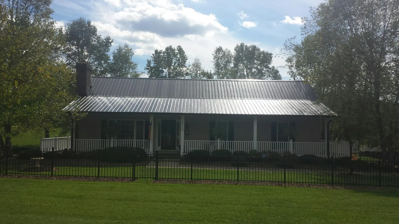 Gray metal roof on a brick ranch with a full width front porch — Gutter Guard Installation work by our crew in Bandera