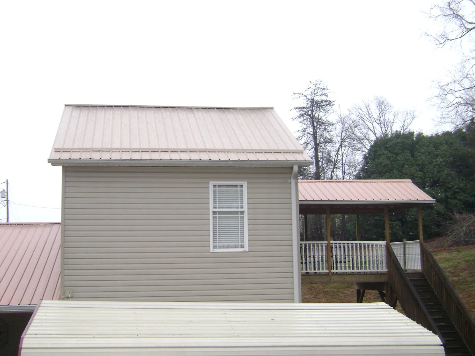 Tan metal roofs on a two story addition and attached porch, from a Roof Replacement job in Bandera