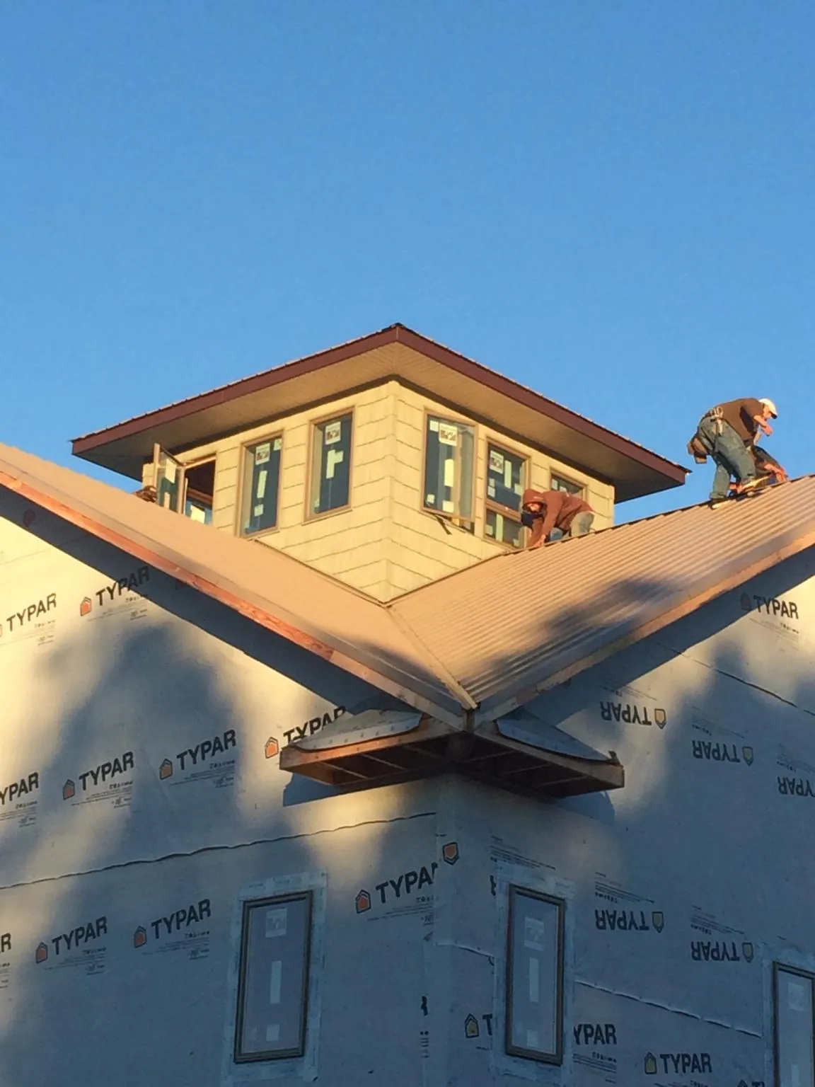 Roofers working around a rooftop cupola on a new metal roof at sunset — Roof Waterproofing in Bandera by Roofing Brothers